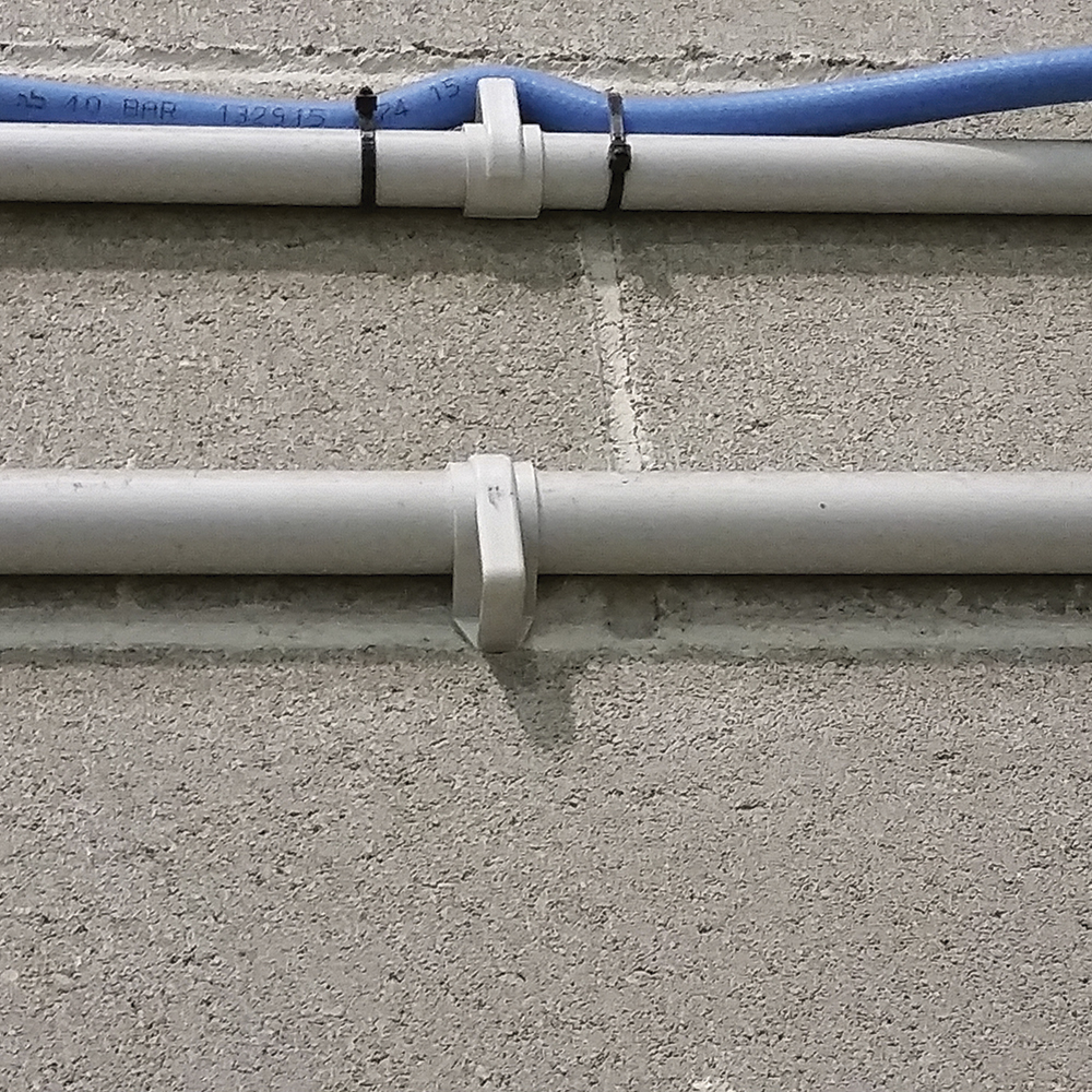 Fijación segura de tubos con grapas plásticas en montaje sobre pared