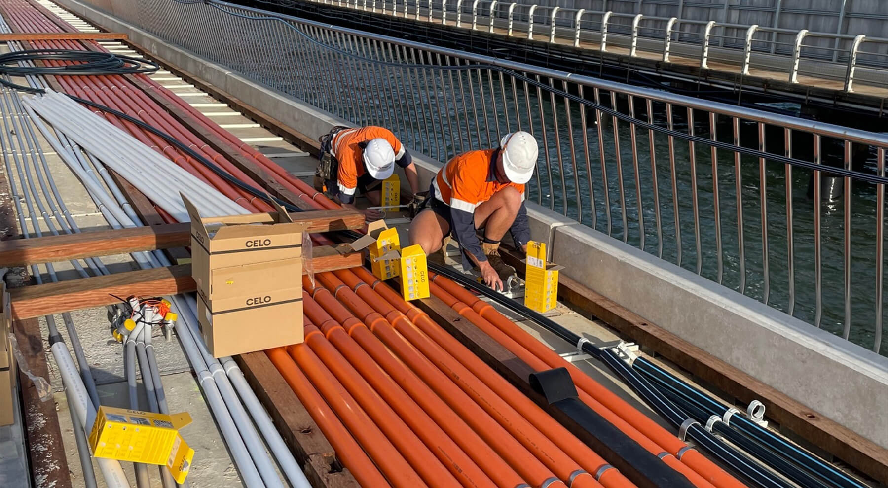 Dos instaladores en el puente de Melbourne instalando abrazaderas SSC de CELO para la sujeción de tuberías